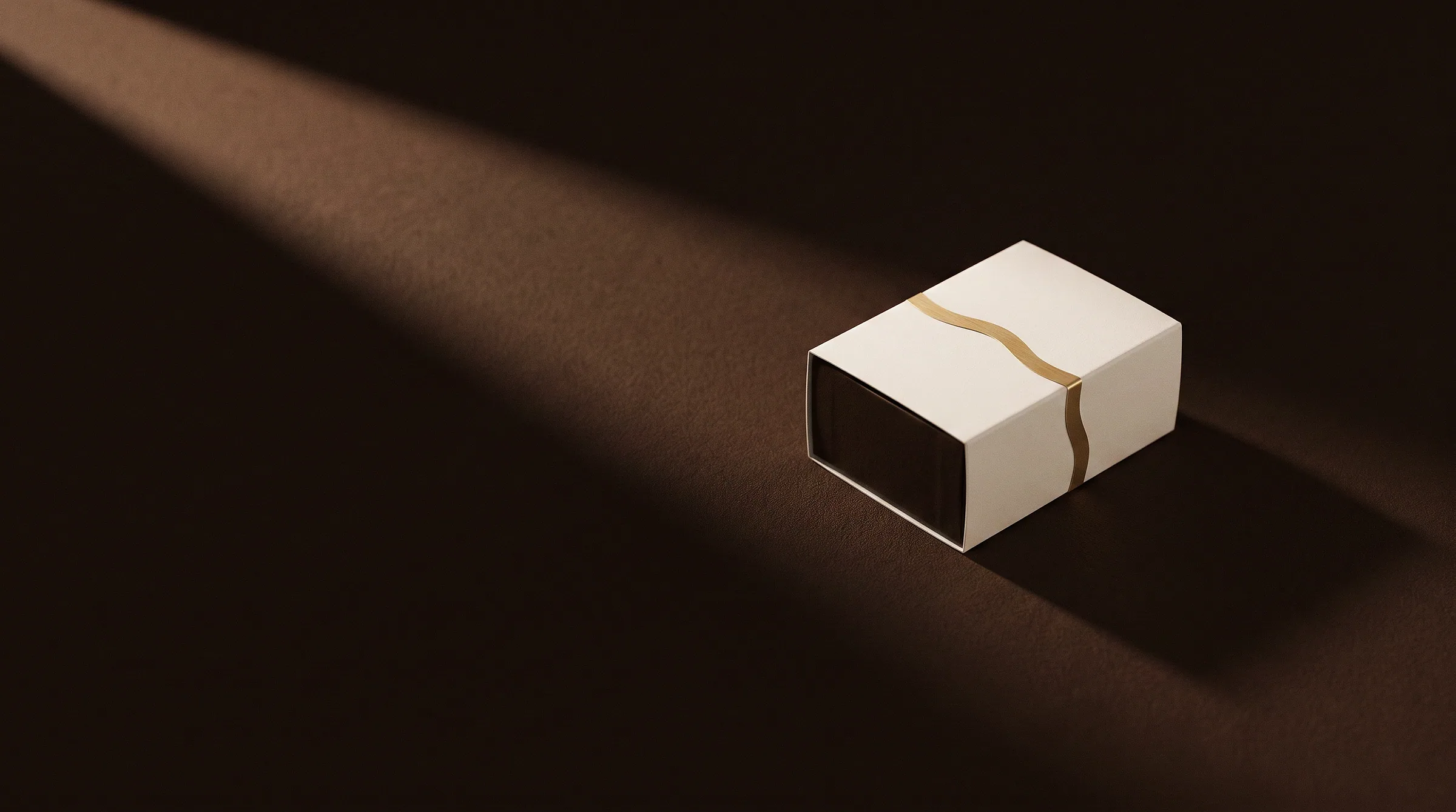 Une boîte Misuu fermée, posée dans un faisceau de lumière chaude sur fond cacao.